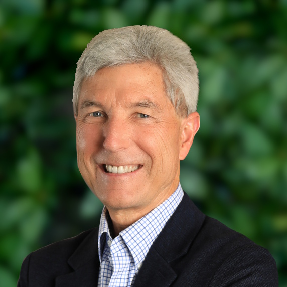Gray haired man in a dark suit smiling