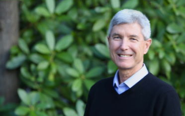 Alan Saunders, VP Sales & Business Development - Grey haired man in a blue sweater on a green leafy background