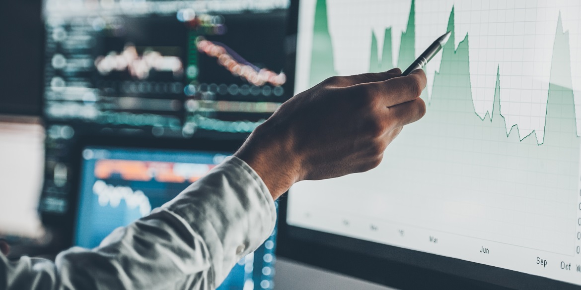 Image of a man's hand holding a pen pointing at a graph on a computer screen - Make the most of your DER interconnection data: virtual metering