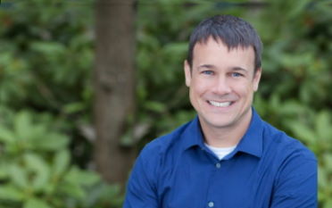 Jeff Ressler, CEO - Image of smiling man in a blue shirt on a green leafy background