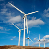 Photo of windmills on a brown hill with blue sky and puffy clouds behind - Minnesota energy