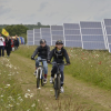 Children on bicycles riding in a field of solar panels - Minnesota solar beats natural gas cost