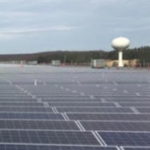 Field of solar panels with a water tower in the distance - Using Modeling and Simulation to Support Grid Resiliency