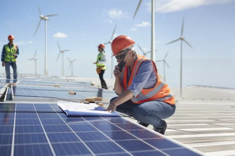Engineer with walkie talkie and blueprint at solar and wind farm